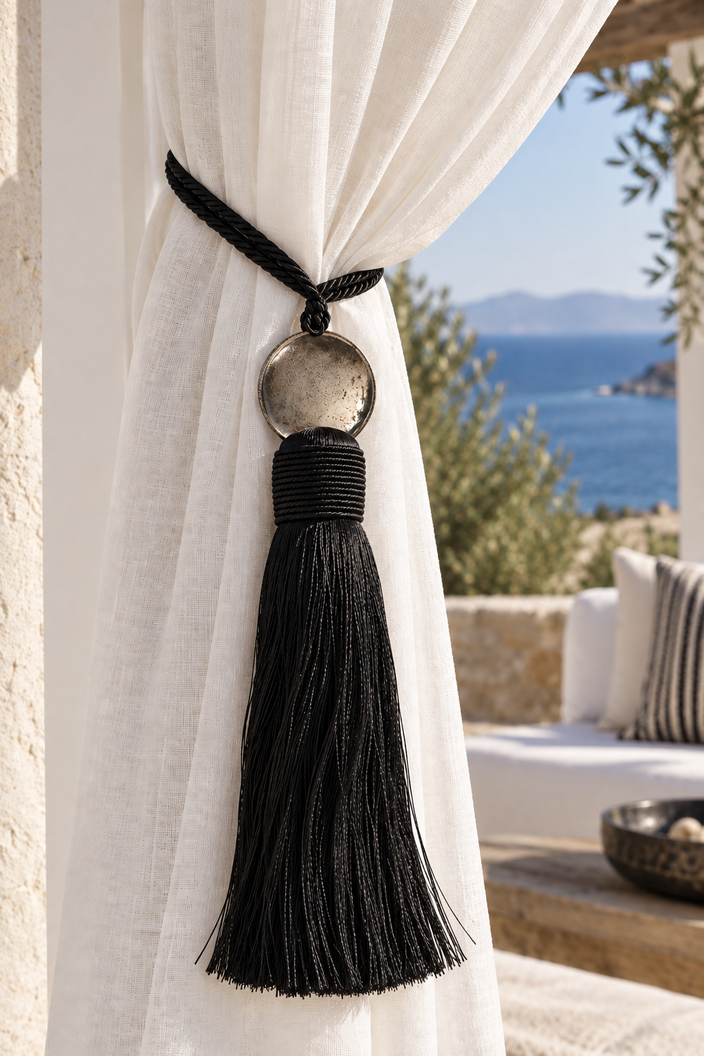 Black Moroccan-style curtain tassel tieback with round aluminium disc, fine satin fringes and twisted tie cords.