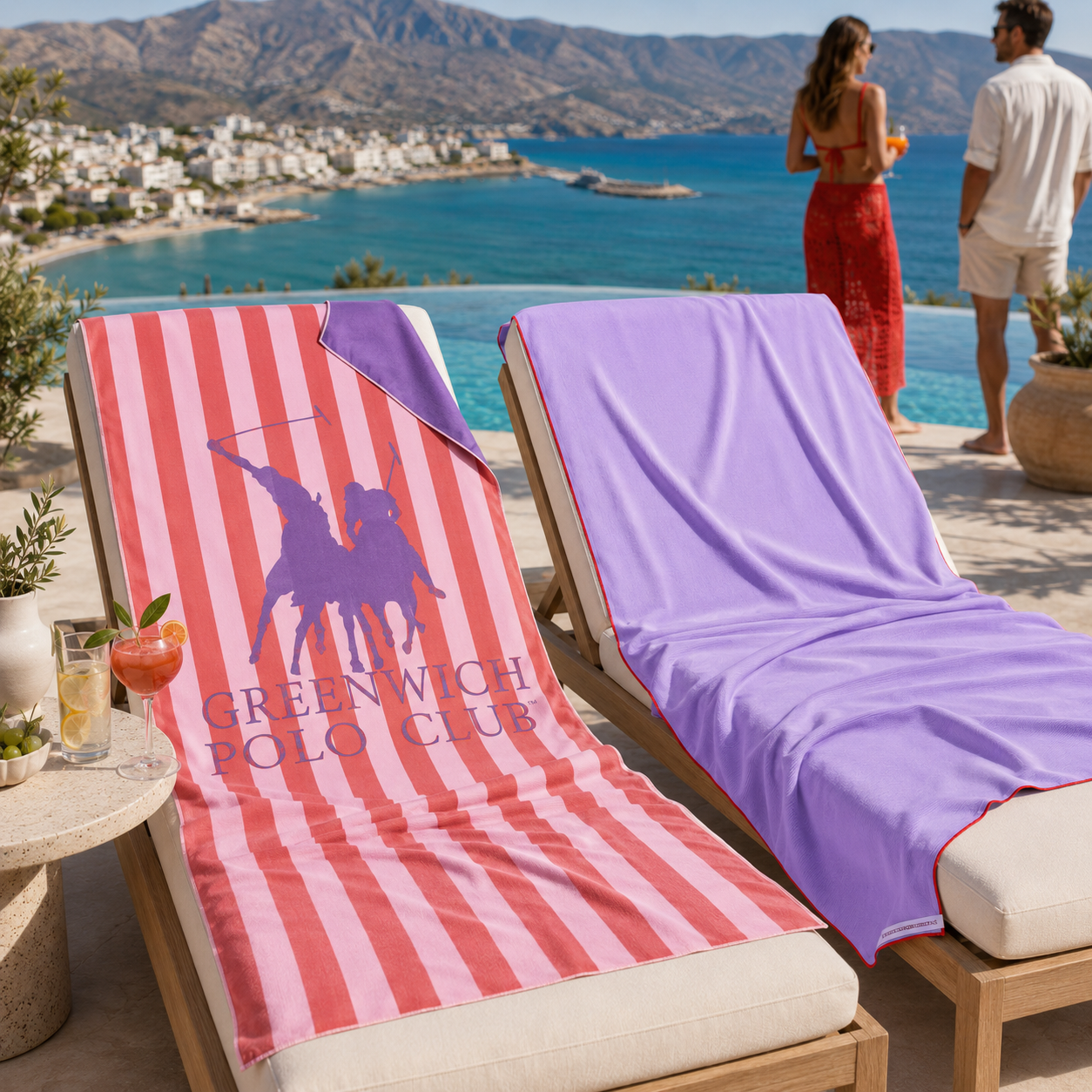Greenwich Polo Club microfiber beach towels 5216 in pink stripes and 5231 in lavender, displayed on sunbeds overlooking Sitia Bay, Crete.