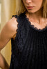 A close-up of a sleeveless black lace top with a flower pattern available in Sitia Paris Fashion