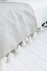 Folded organic cotton blanket in gray with white pompoms small by VVC™, sustainably made with soft texture and pompoms.