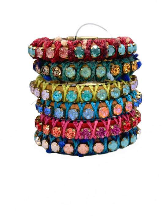 A stack of colorful bracelets with leather bands and multicolored Swarovski crystals.