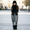 Woman wearing a black coat, black hat, and gray pants in an urban setting