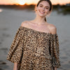 Model wearing off-shoulder camel leopard dress on Crete coast