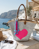 Handmade silver sequin beach basket with neon pink heart embroidery, brown leather handles and decorative tassel charm. Luxury oversized summer tote bag designed for beach holidays, shopping and Mediterranean resort wear.