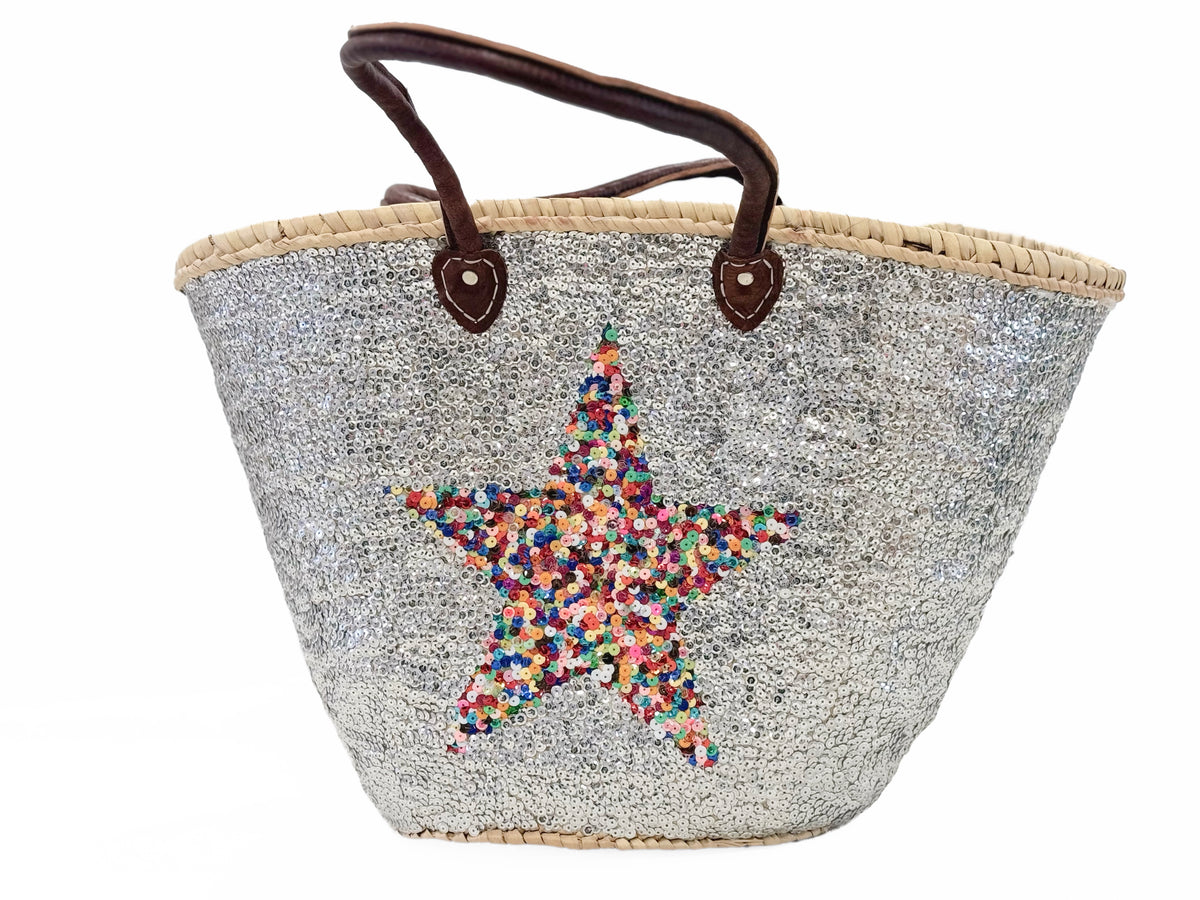 A handmade silver basket with a sequin star decoration and a brown leather handle.