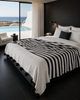 Folded VVC organic cotton striped blanket in black and off-white, handmade in Morocco with soft woven texture and black wool pompoms for bedroom styling