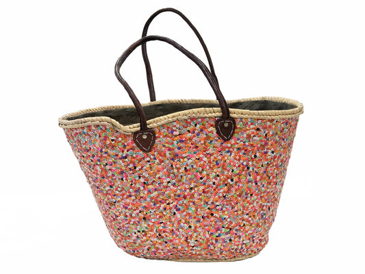 A multicolored palm leaf basket with embroidered sequins and brown leather handles.