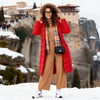 Woman in a red coat and beige outfit standing in a snowy landscape with rock formations.