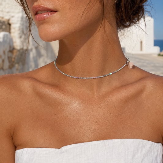 Woman wearing a rainbow rhinestone choker necklace with blush textile flower by VVC Shop Sitia, Crete.