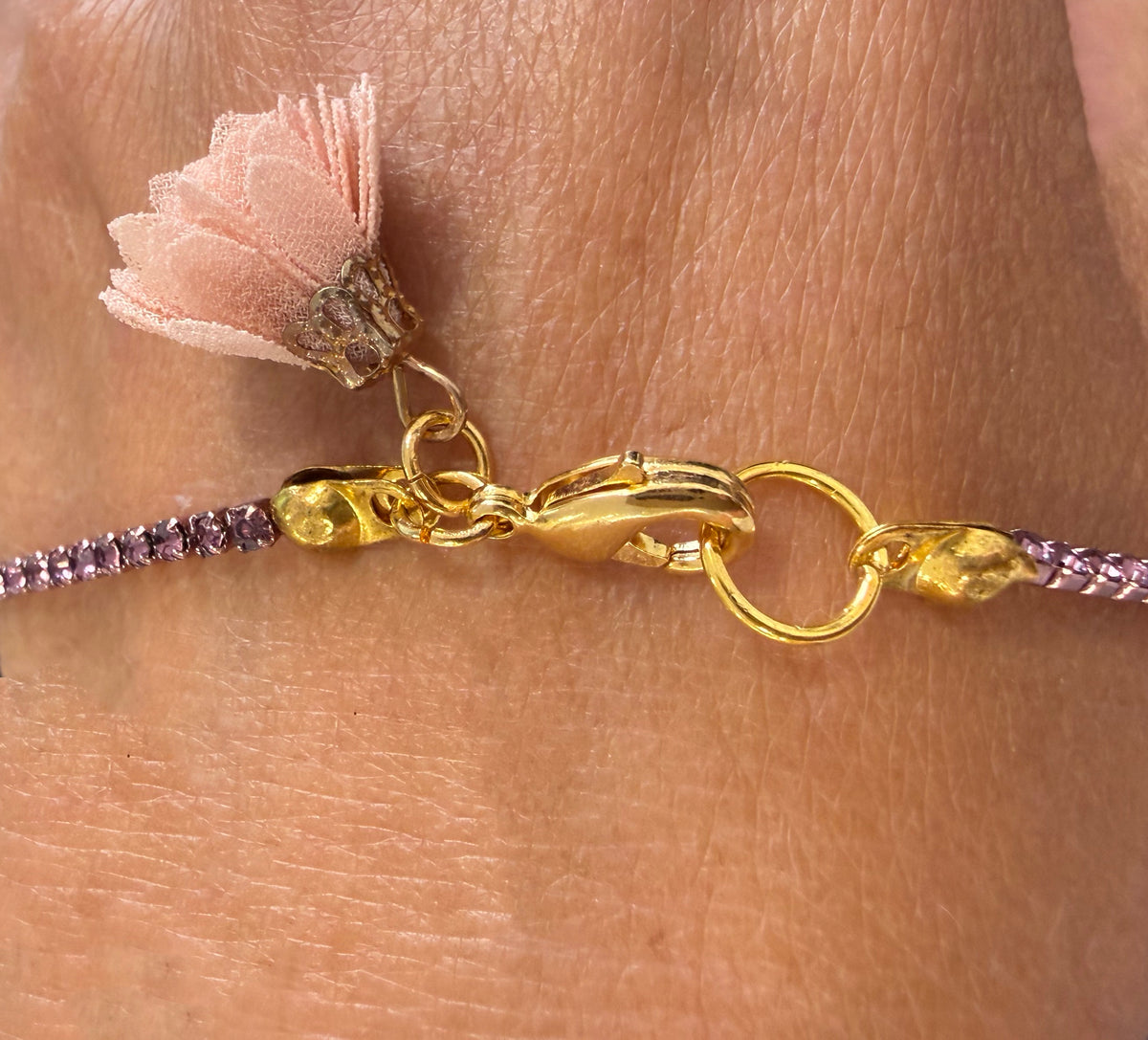 Create alt text close up of golden necked closerure with small textile flower 