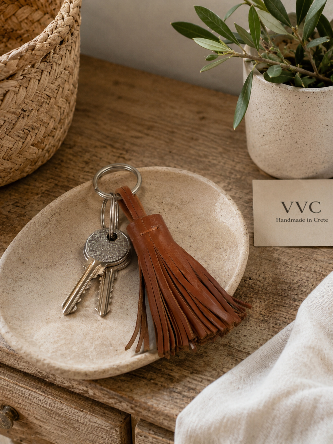 Luxury lifestyle image of a handmade camel brown leather tassel keyring with stainless steel ring, photographed with elegant accessories and designer handbag.