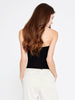Back close-up of the Berrin black bandeau bustier showing its concealed zipper, styled with white trousers.