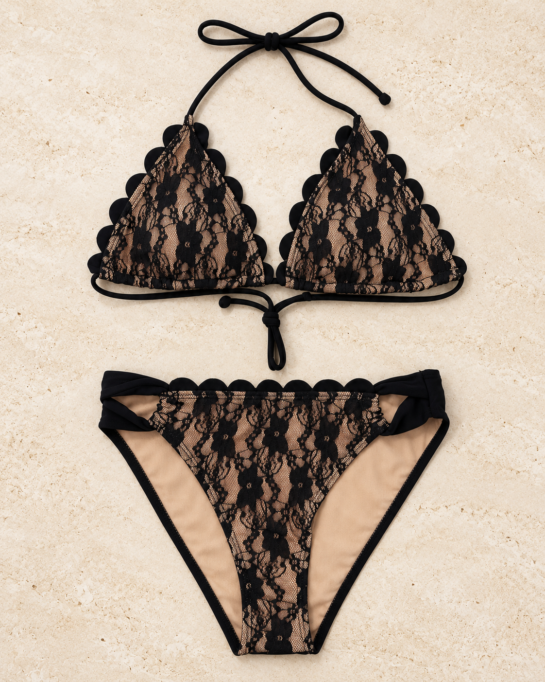 A two-piece bikini set featuring black lace with scalloped edges and black trim, laid flat on a textured beige background. The top has triangle cups with side ties, and the bottom is a high-cut style with side ties.