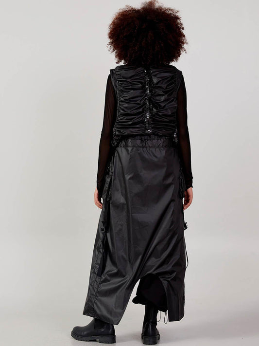 Back view of a women’s black long cardigan vest with subtle sequin detailing and adjustable straps at VVC SHOP Sitia