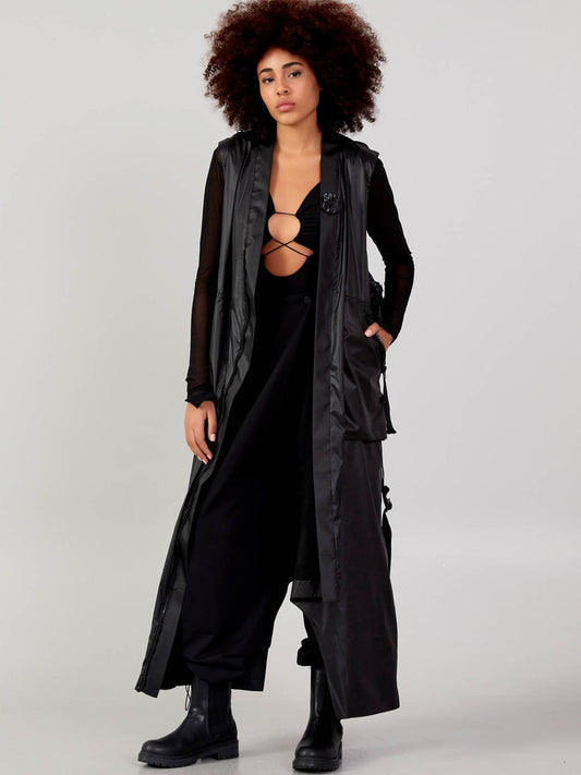 Front view of a women’s black long cardigan vest with adjustable waist straps and zip pockets, available at VVC SHOP Sitia