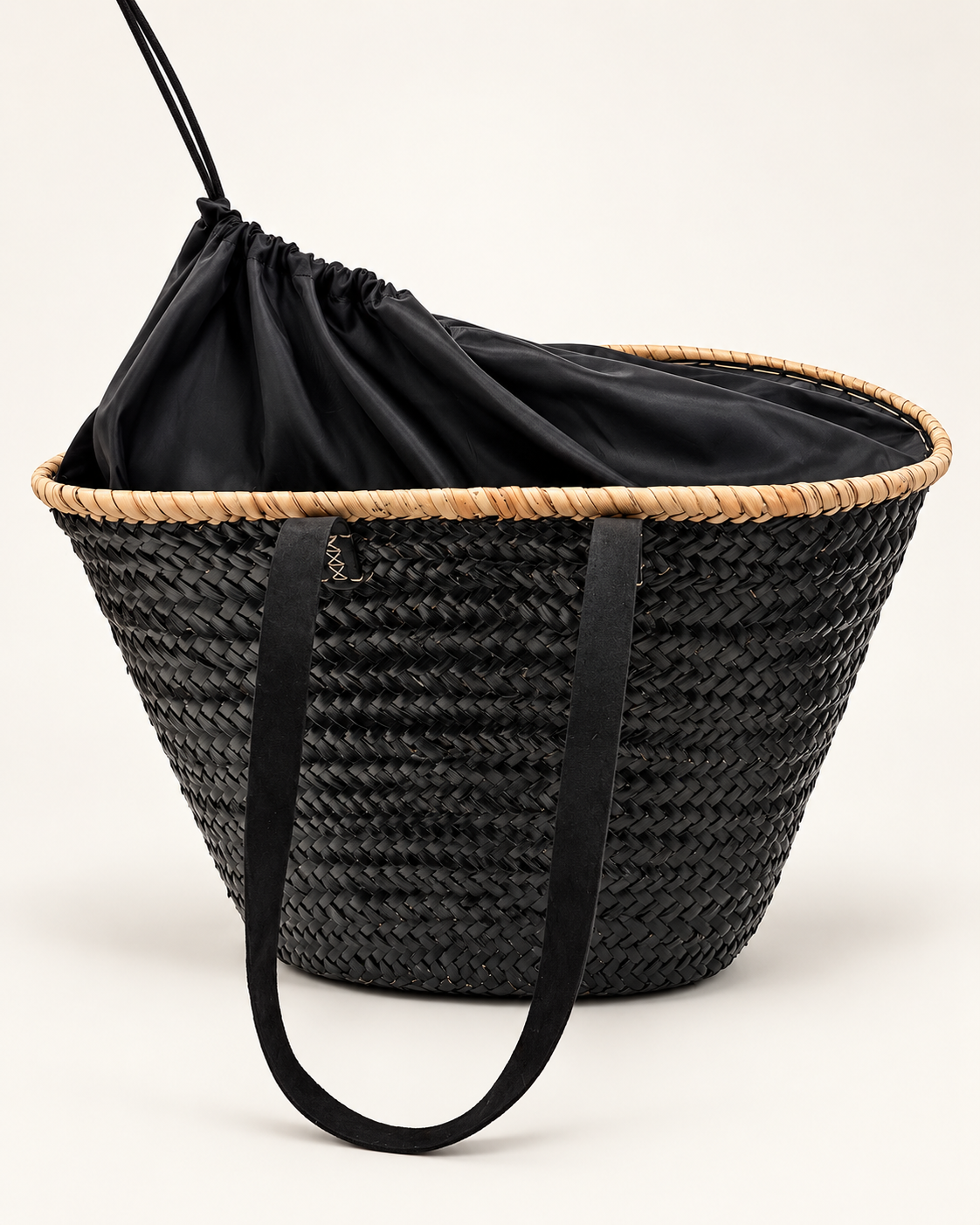 Large black raffia basket bag on white background with natural raffia trim, shoulder handles and drawstring closure.