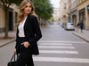 Side view of a woman wearing black slim-fit fine-knit wool jogger trousers in an urban setting.