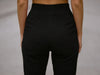 Close-up front view of black slim-fit fine-knit wool jogger trousers showing the elastic waistband.