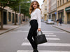 Back view of a woman walking in black slim-fit fine-knit wool jogger trousers while carrying a black bag.