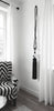 Black and white armchair next to a wall with a long black tassel hanging from a hook.