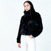 Close-up of a black cropped faux fur jacket on a white studio background, highlighting the soft texture and detailed faux fur finish.