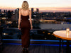 Three-quarter back view of a woman wearing the brown spaghetti-strap bodycon dress at sunset.