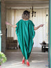 Full back view of an emerald green plus-size kaftan with flowing batwing sleeves, oversized fit and a longer asymmetric mullet hem