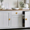 Gold Monstera leaf furniture knobs fitted to a white cabinet in a bright interior.