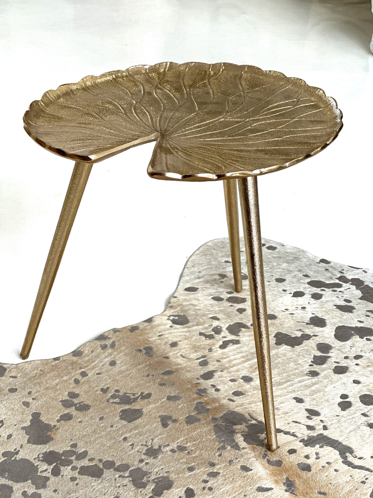 Side view of the Gold Lilly accent table sculptural design with three legs, small and portable 