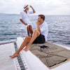 Couple relaxing on a yacht with the Greenwich Polo Club 5236 taupe and black striped beach towel.