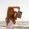 Woman holding the Greenwich Polo Club 3861 black and beige leopard-print cosmetic bag beside the sea.
