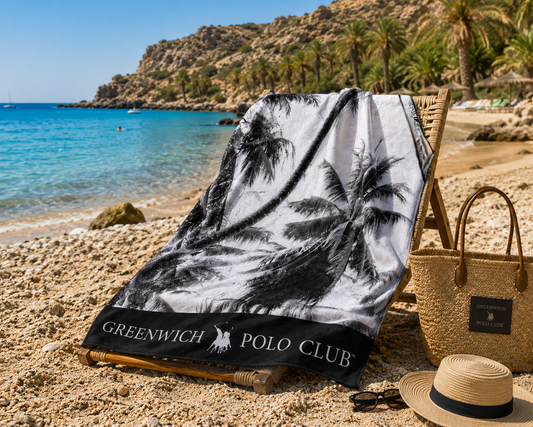Greenwich Polo Club palm-tree microfiber beach towel 3875, 80 × 170 cm, displayed on a sun lounger beside the beach.