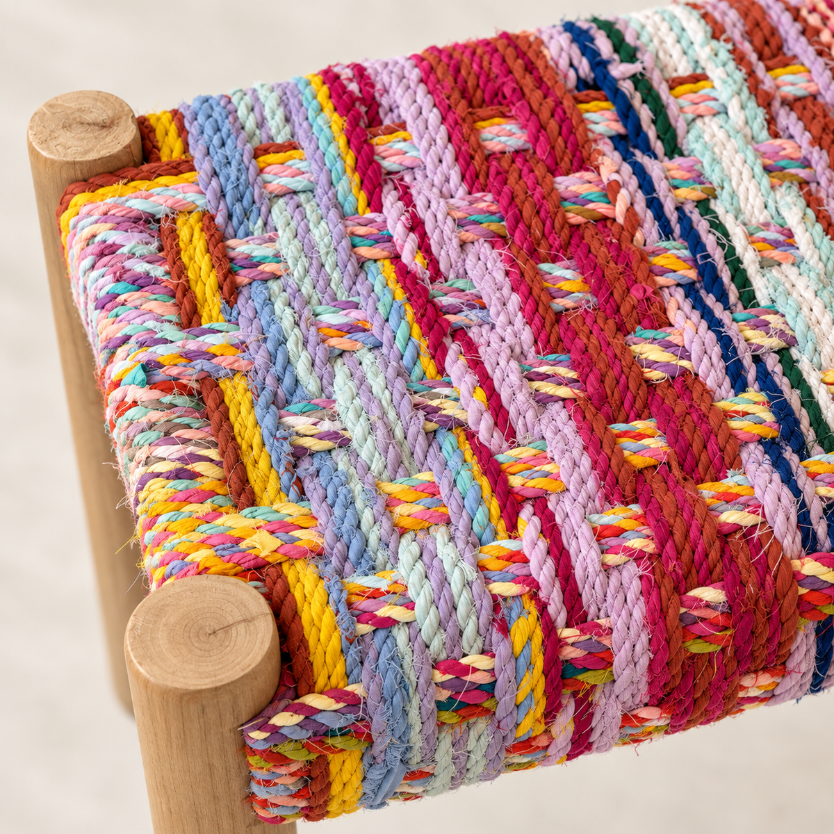 Close-up of handmade recycled textile weaving around the natural wood corner of the bench.