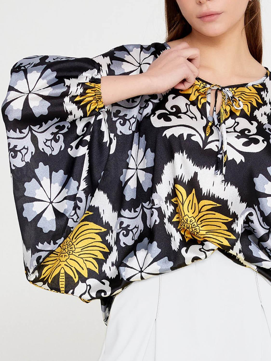 Front view of Imza loose fit palm tree blouse with black base, yellow palm design, grey and white accents and tie neckline