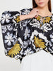 Front view of Imza loose fit palm tree blouse with black base, yellow palm design, grey and white accents and tie neckline