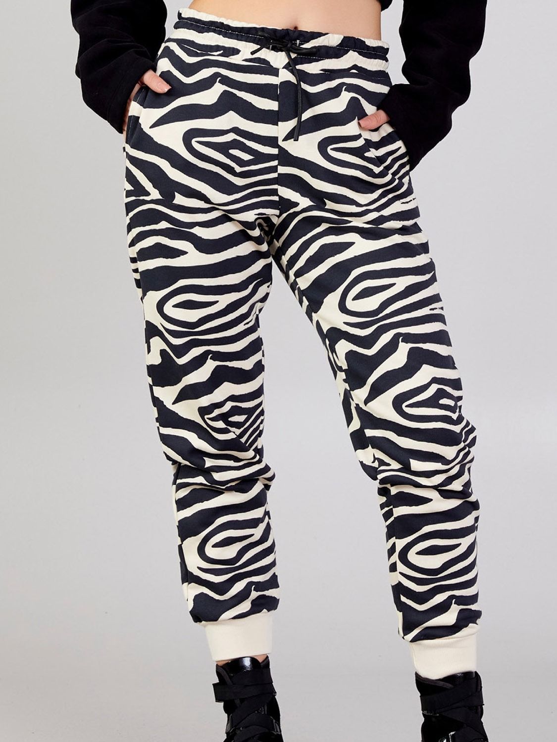 Full-length front view of a model wearing Kasha beige-and-black zebra-print cotton-blend jogger pants with a black top.