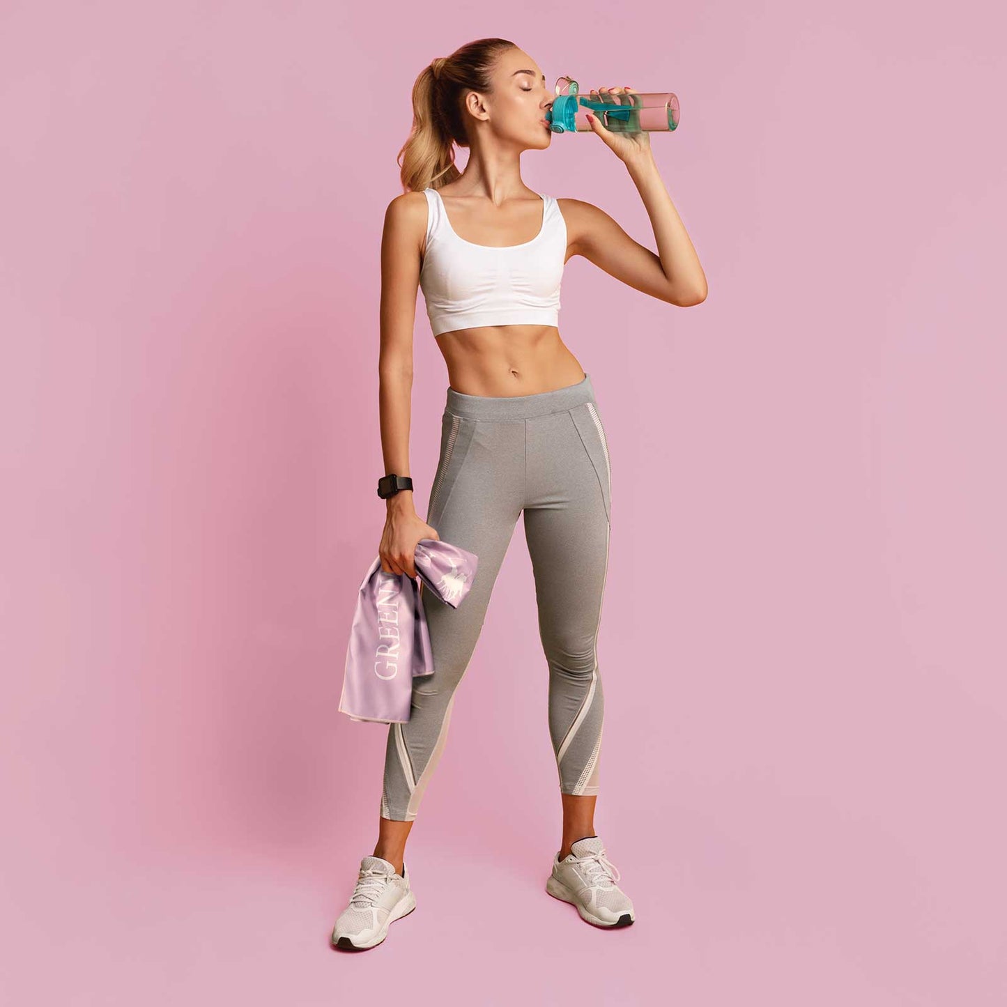Woman in athletic wear drinking from a water bottle on a pink background Super-soft pink sports towel with vertical Polo Club logo
