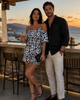 MiandMi black and white animal print viscose shorts jumpsuit shown from above while seated at a golden-hour bar in Mochlos, Crete, highlighting the cold-shoulder sleeves and spaghetti straps.