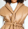 Close-up of the camel-brown Daunt hooded vest by Michaela MII with an adjustable waist belt and wide arm openings.