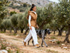 Side view of a woman wearing the Michaela MII camel-brown hooded Daunt vest with its belt tied at the waist.