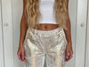 Detailed close-up of gold shimmer fabric and waist belt accents — luxury shine pants on sale at VVC Shop Sitia.