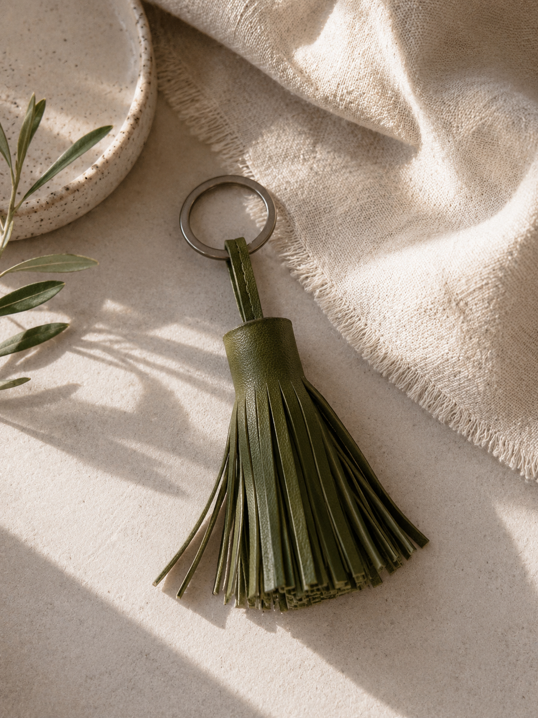 Olive green leather tassel key chain handmade in Crete, photographed in a natural lifestyle setting, available in Sitia Crete and online