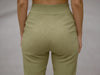 Close-up back view of olive-green slim-fit fine-knit wool jogger trousers showing the elastic waistband.
