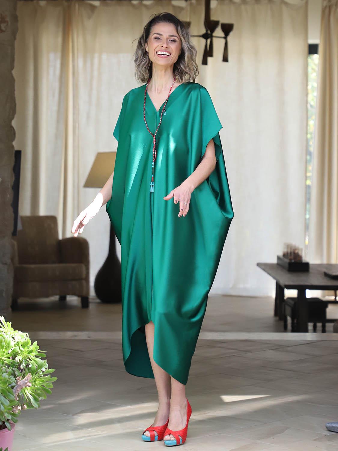 Woman wearing an emerald green plus-size kaftan by Pane Line with V-neckline, batwing sleeves and an asymmetric mullet hem