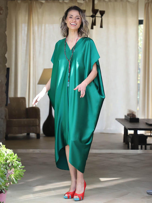 Woman wearing an emerald green plus-size kaftan by Pane Line with V-neckline, batwing sleeves and an asymmetric mullet hem