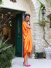 Full-length side view of the Panoe Line orange plus-size maxi kaftan with batwing sleeves and an asymmetric mullet hem.