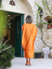 Back view of the Panoe Line orange plus-size maxi kaftan showing its batwing sleeves and longer mullet hem at VVC SHOP Sitia.