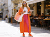 Woman wearing pink slim-fit fine-knit wool jogger trousers with an orange coat in a city setting.
