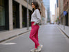 Side view of a woman wearing pink slim-fit fine-knit wool jogger trousers with narrow ankle cuffs.