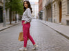Side view of a woman walking in pink slim-fit fine-knit wool jogger trousers on a city street.